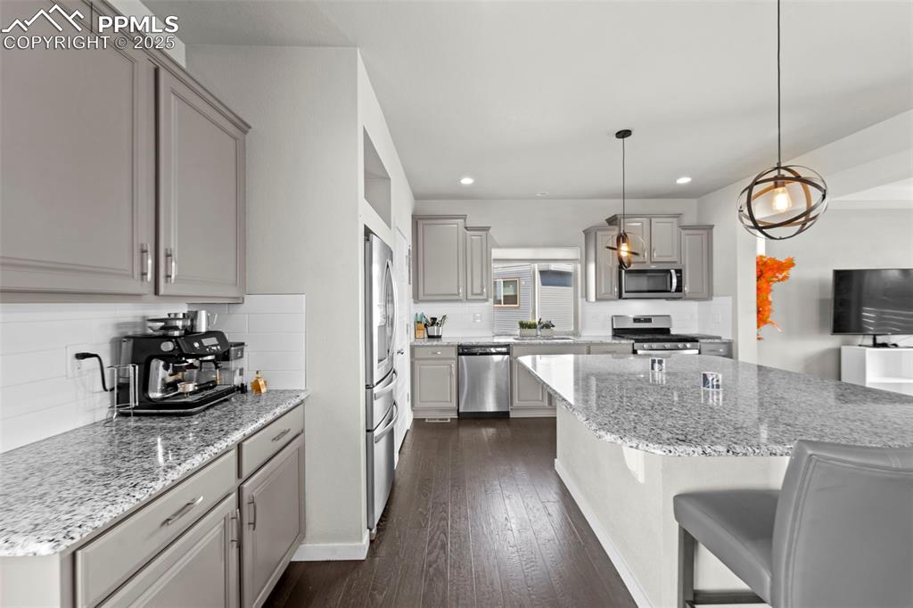 Image 7 of 30: Kitchen with gray cabinets, light stone countertops, dark wood-type floorin