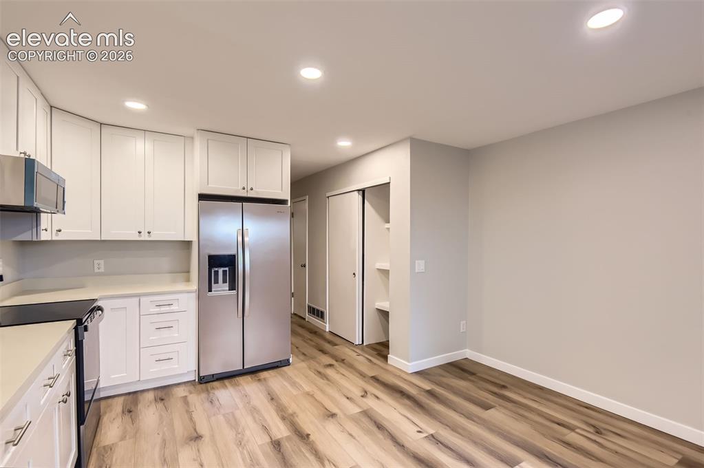 Image 11 of 32: Kitchen featuring white shaker cabinetry, stainless steel appliances, light