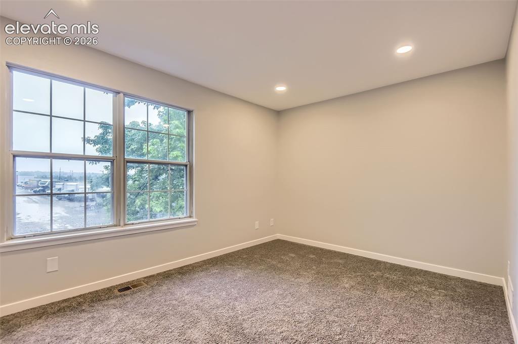 Image 17 of 32: Room with a large double window featuring white grilles, light beige walls,