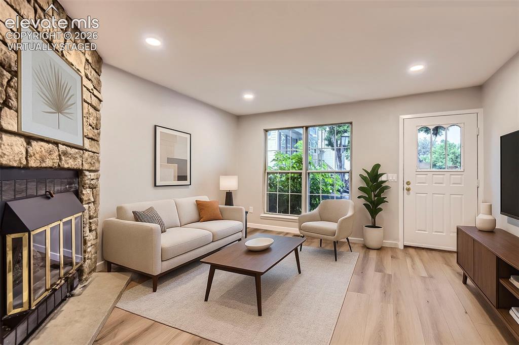 Image 2 of 32: Living area featuring a stone-clad fireplace with a black firebox, wood-fin
