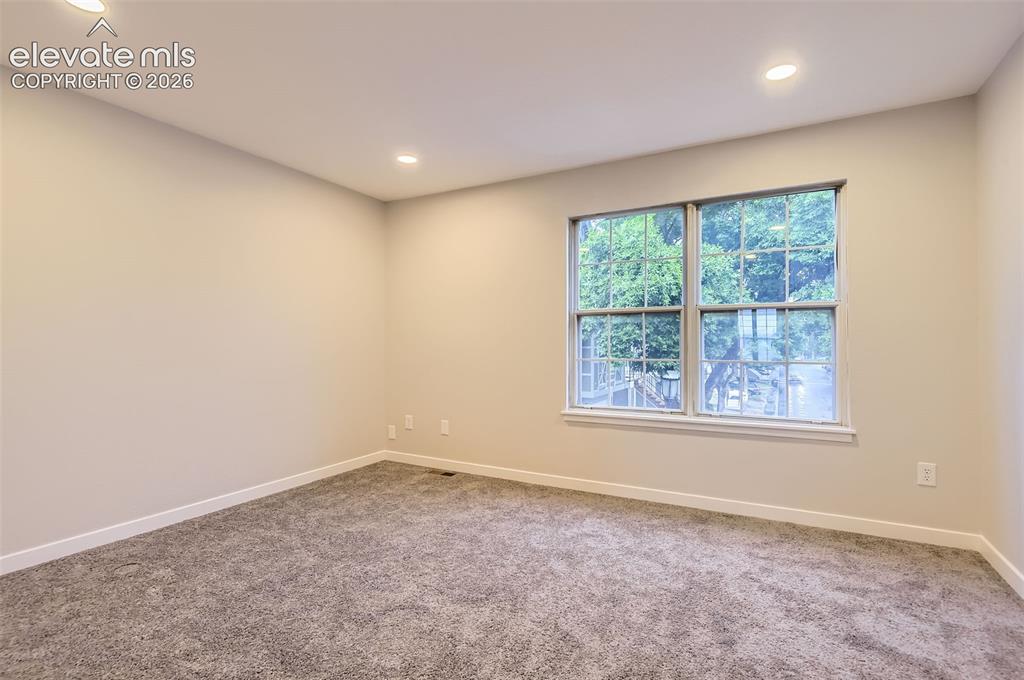 Image 23 of 32: Neutral-toned room featuring a large window, recessed lighting, plush carpe