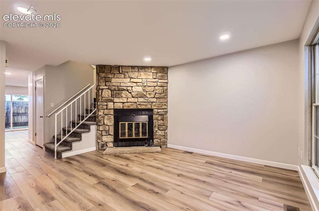 Image 4 of 32: Living space featuring a stone-clad fireplace with a black firebox and hear