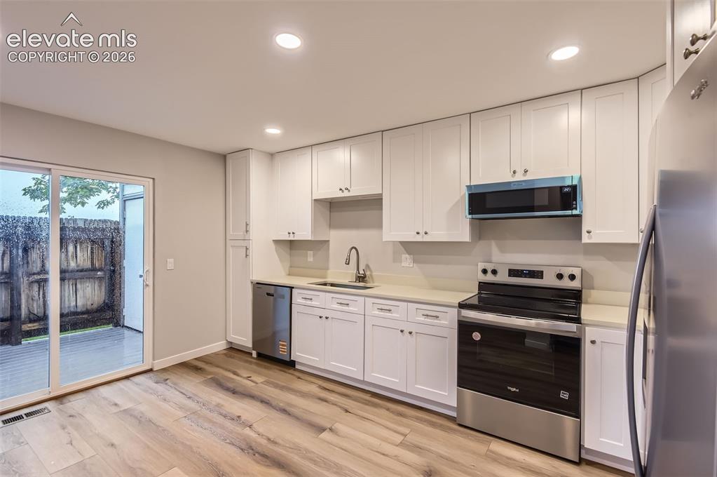 Image 9 of 32: Contemporary kitchen featuring white cabinetry, light-toned countertops, an