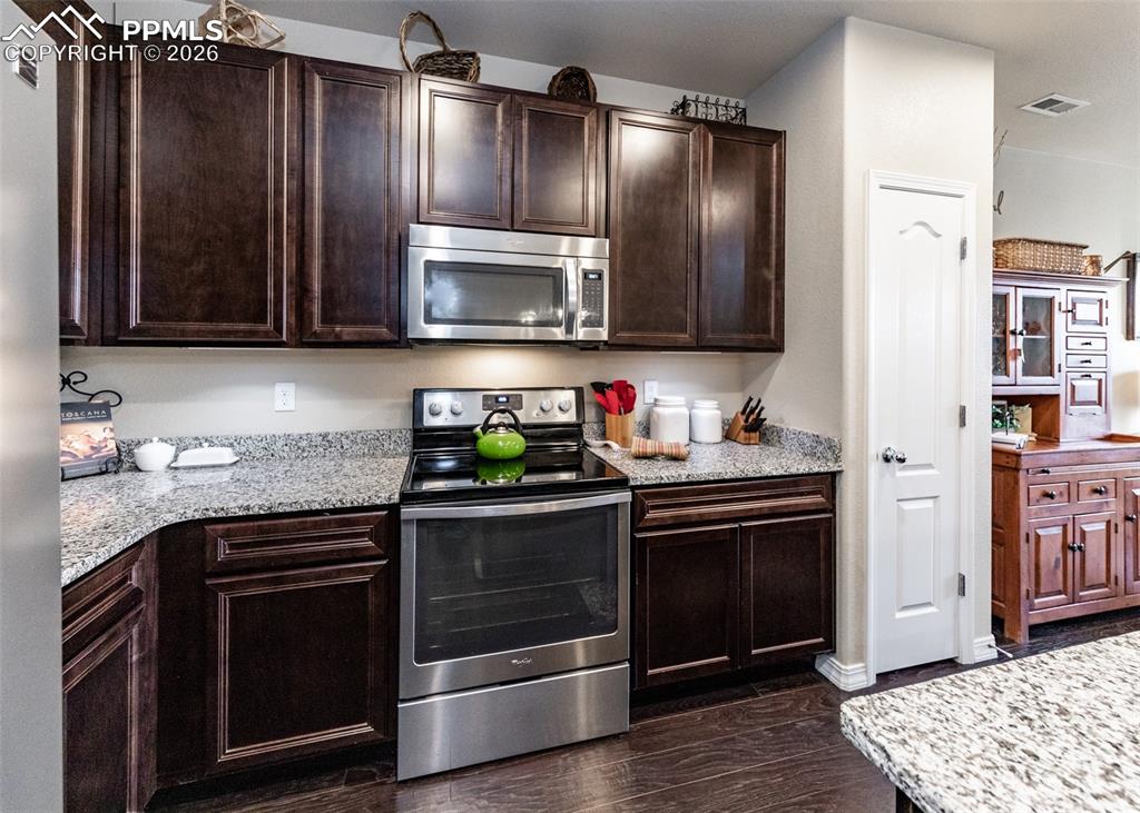 Image 11 of 32: Kitchen featuring appliances with stainless steel finishes, dark brown cabi