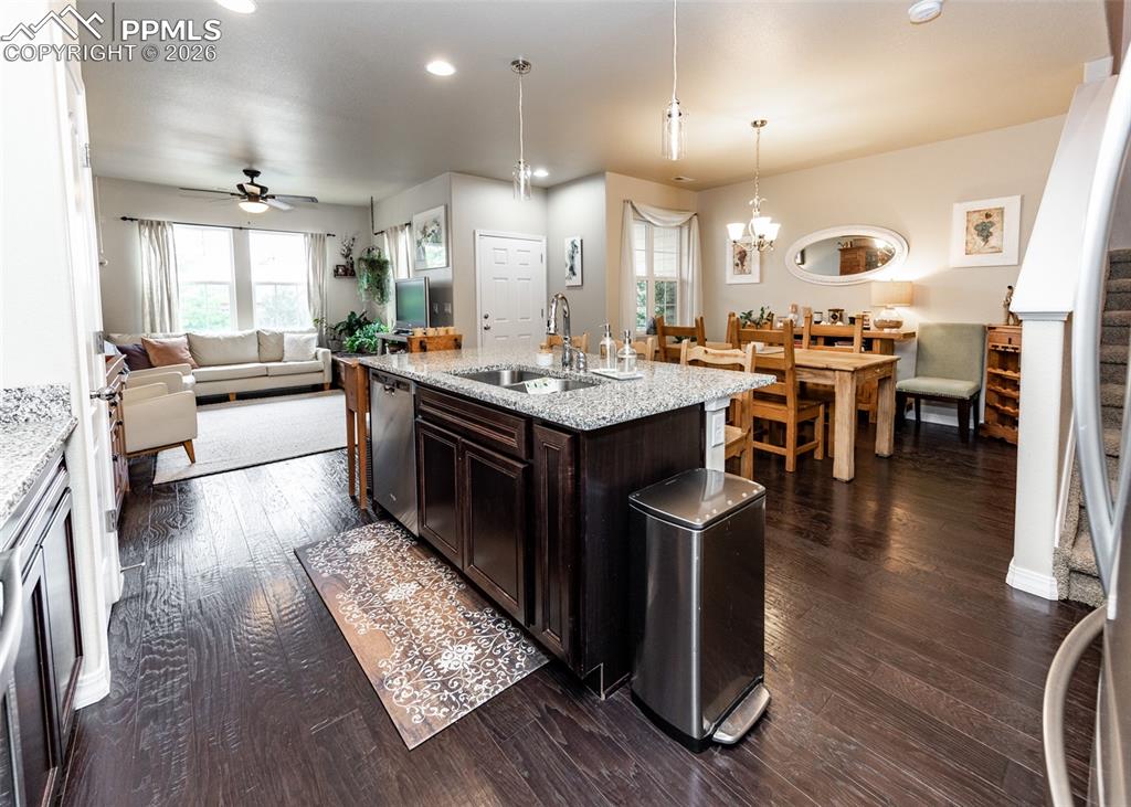 Image 12 of 32: Kitchen featuring dark brown cabinets, dark wood-style floors, open floor p