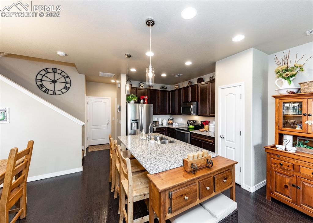 Image 13 of 32: Kitchen with dark brown cabinets, pendant lighting, appliances with stainle