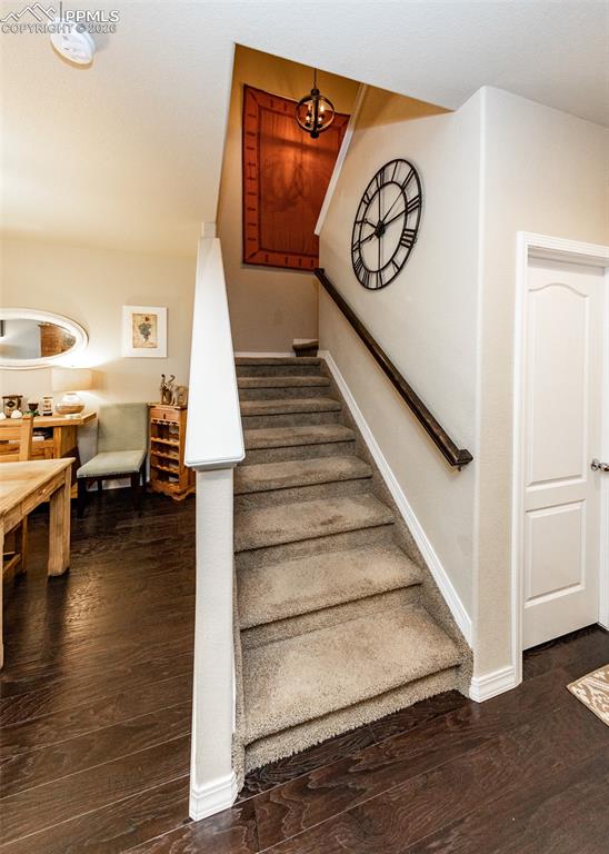 Image 16 of 32: Stairway with wood finished floors and a chandelier