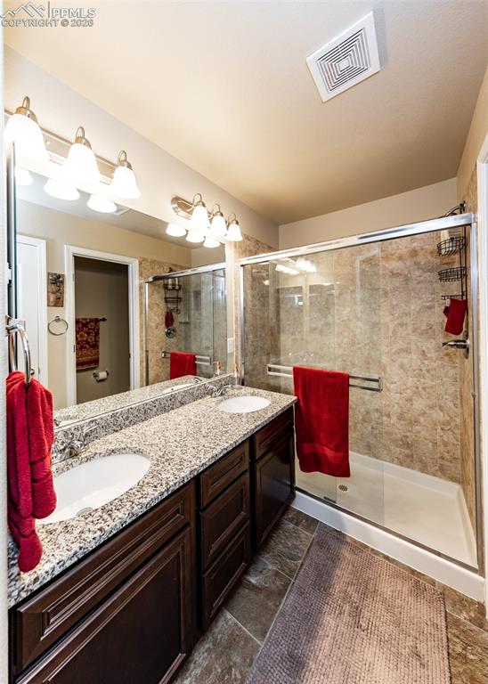 Image 28 of 32: Bathroom with double vanity and a stall shower