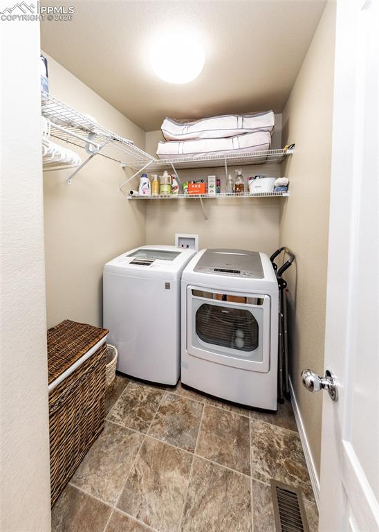 Image 31 of 32: Laundry area with independent washer and dryer and dark stone finish floori