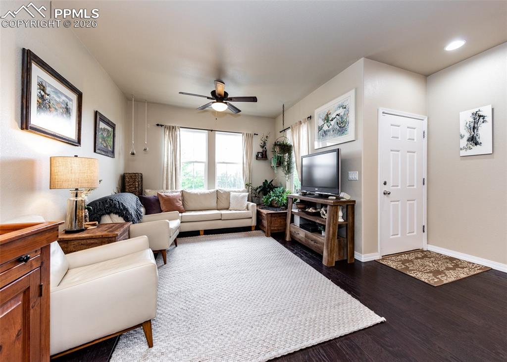 Image 5 of 32: Living room with dark wood-type flooring and ceiling fan
