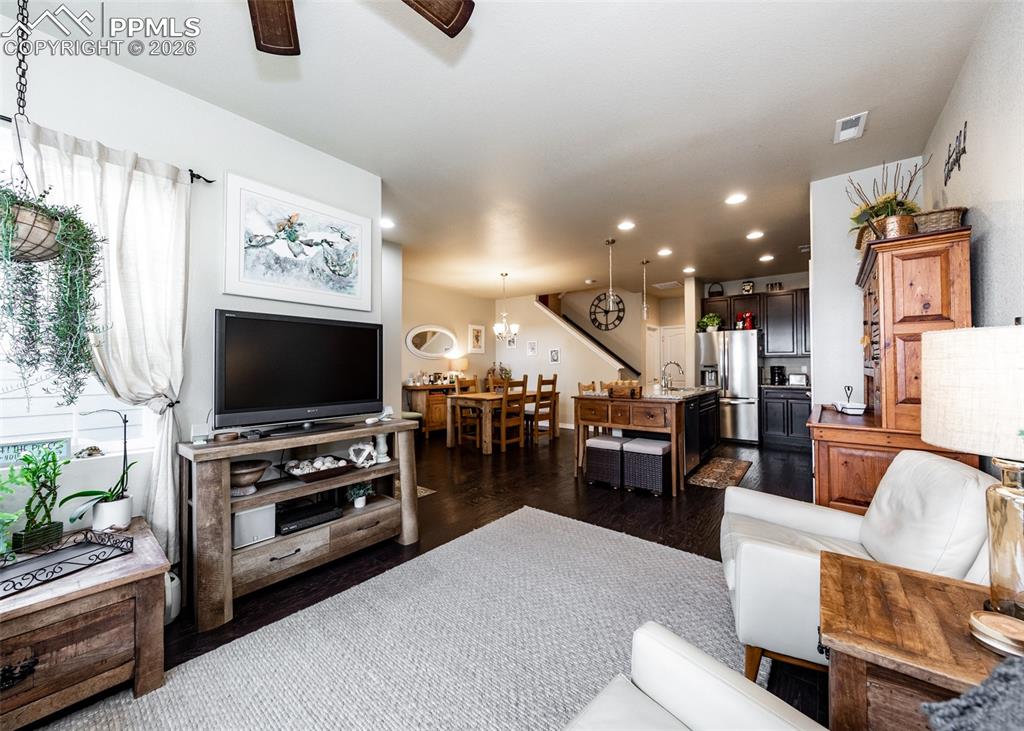 Image 6 of 32: Living area featuring dark wood-style floors, recessed lighting, a chandeli