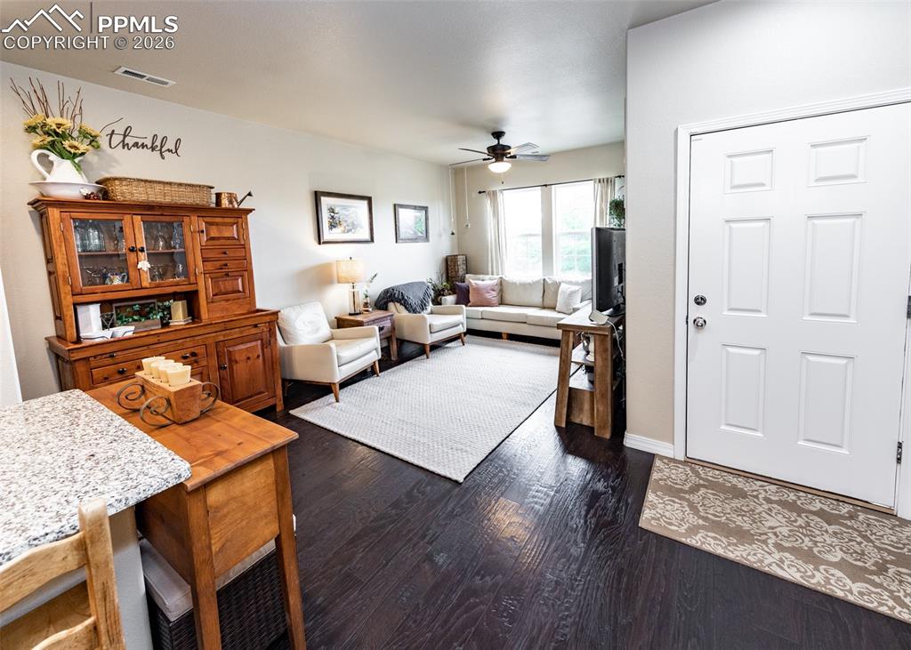 Image 7 of 32: Living area with dark wood finished floors and a ceiling fan