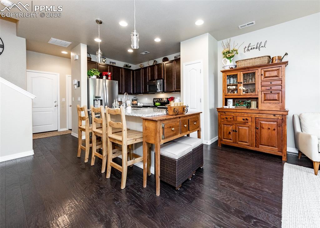 Image 8 of 32: Kitchen featuring dark wood-style floors, pendant lighting, dark brown cabi