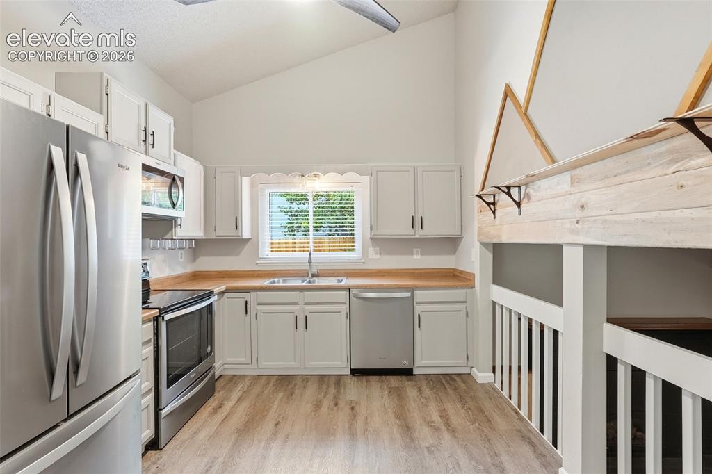 Image 13 of 35: Kitchen featuring vaulted ceilings, light wood-finish flooring, white cabin