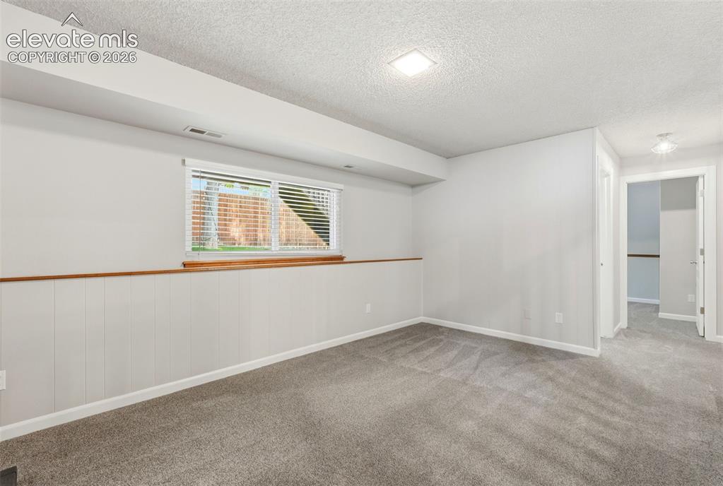 Image 17 of 35: Spacious room featuring light gray walls, plush gray carpeting, and white p