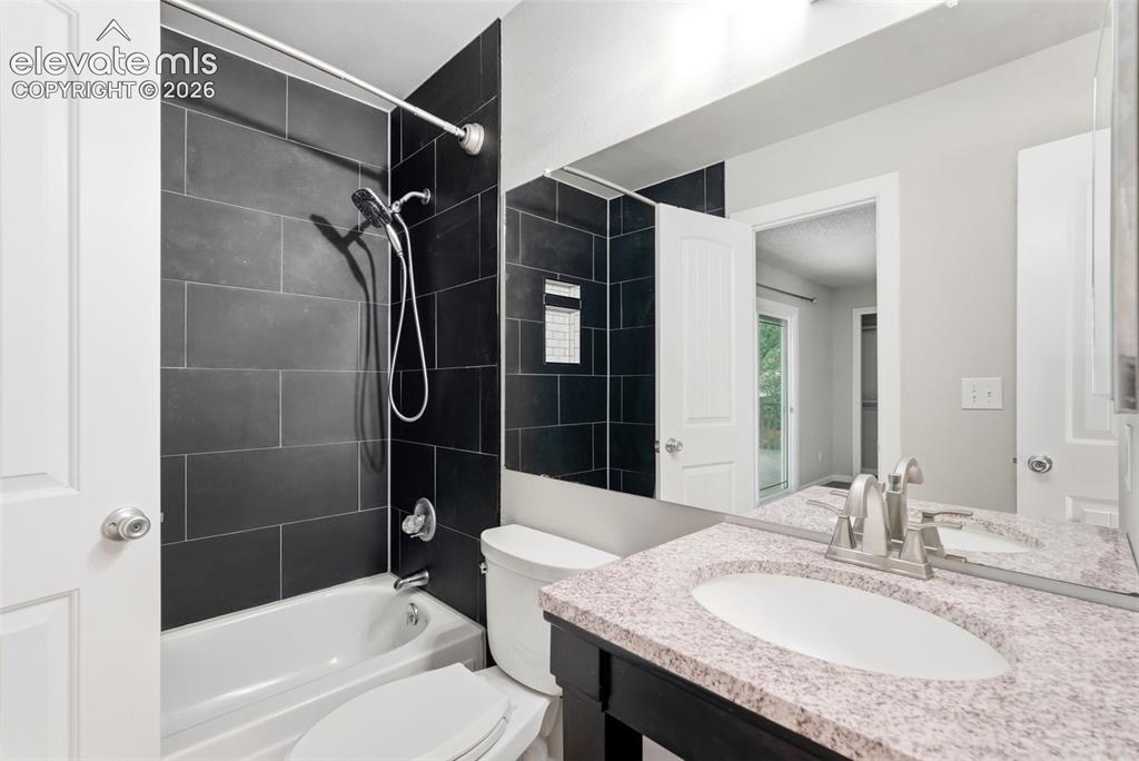 Image 18 of 35: Bathroom featuring a full-size tub with dark tiled surround and a shower he