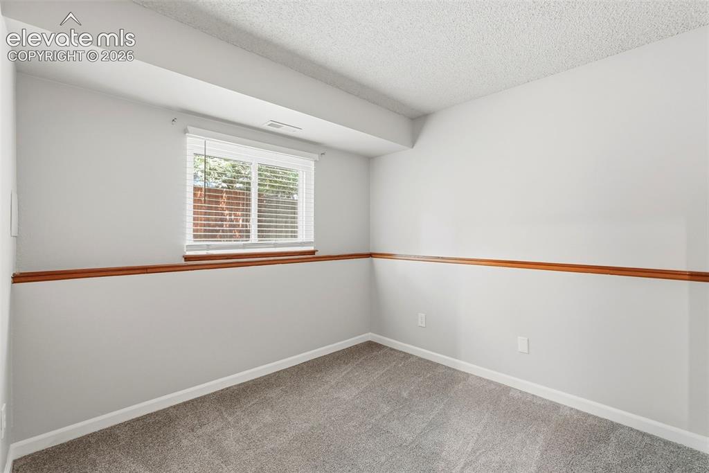 Image 19 of 35: Bright room featuring light grey walls with a mid-height wood trim accent