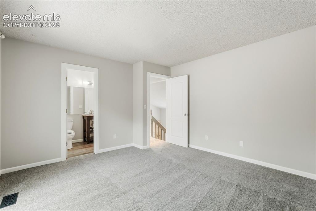 Image 23 of 35: Spacious room featuring light gray walls, textured white ceilings, and gray