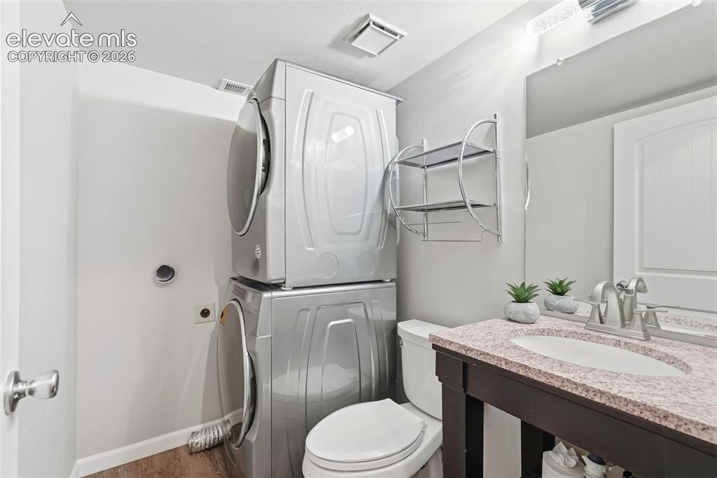 Image 24 of 35: Compact laundry area featuring a stacked washer and dryer