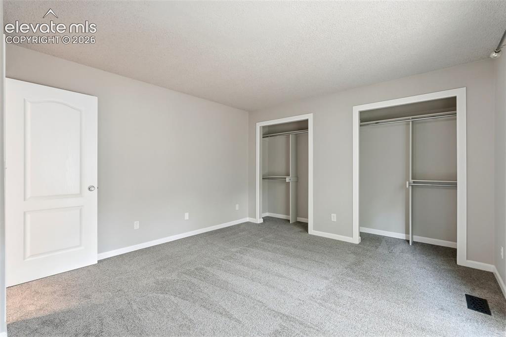 Image 25 of 35: Spacious room featuring light gray walls, gray carpeting, dual closet space