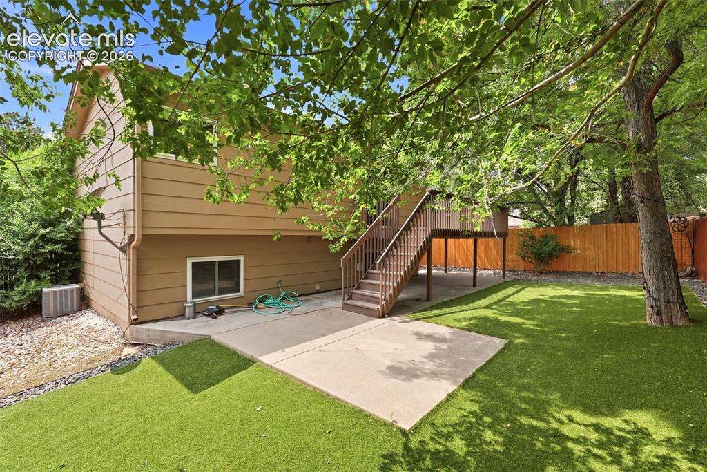 Image 28 of 35: Expansive backyard featuring a large concrete patio, artificial turf, and m