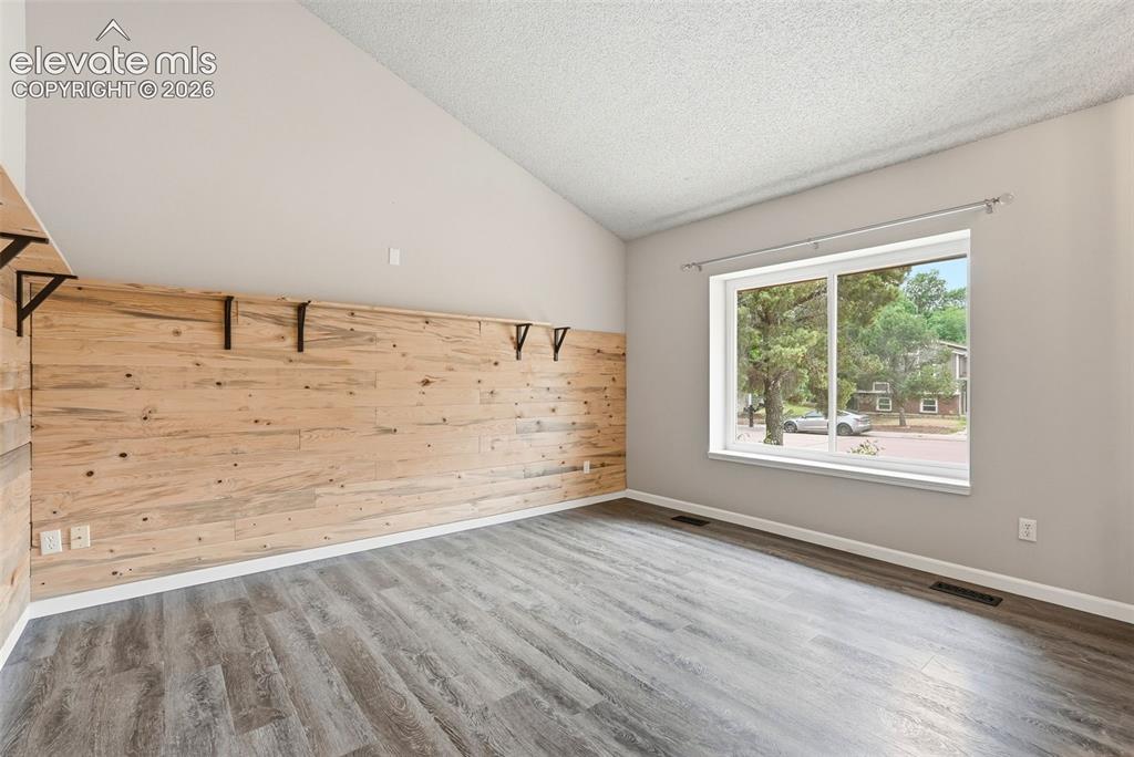 Image 4 of 35: Room featuring a prominent wood-panel accent wall with mounted shelf bracke