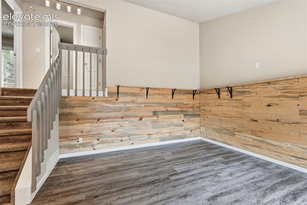 Image 7 of 35: Open living area featuring wood-finish flooring, accent wood paneling, and