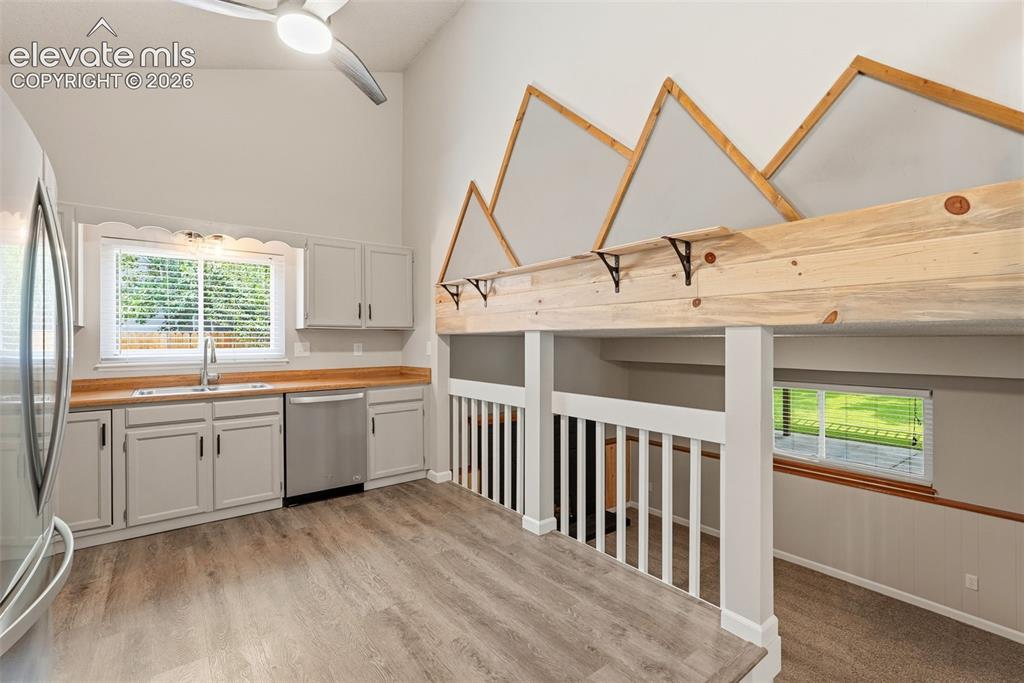 Image 8 of 35: Kitchen area featuring light gray cabinetry, wood-finish countertops, and s