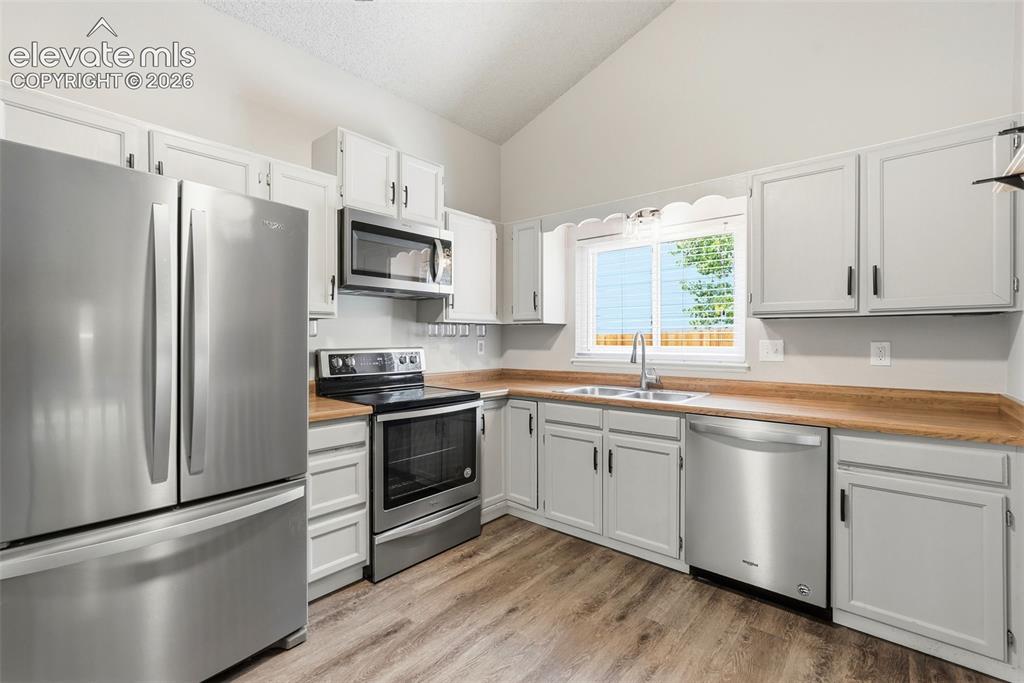 Image 9 of 35: Kitchen featuring vaulted ceilings, stainless steel appliances, wood-finish