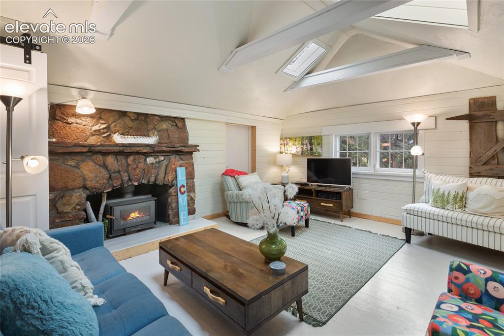 Image 14 of 42: The living room has gorgeous accents, skylights and a wood burning stone fi