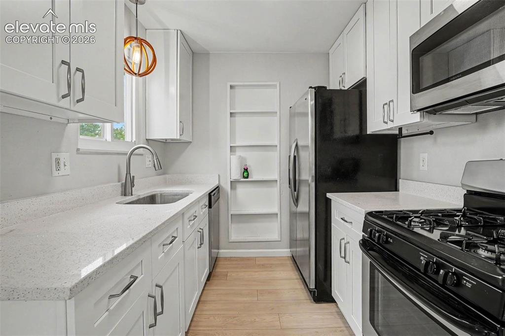 Image 13 of 27: Open-concept kitchen and dining area featuring light wood-finish flooring, 
