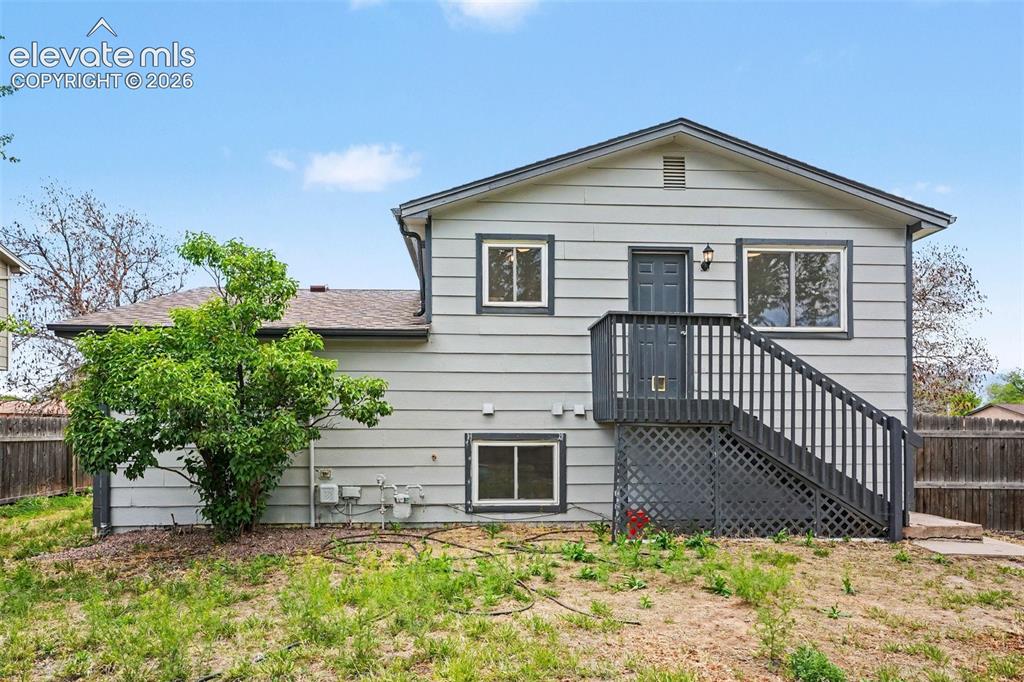 Image 25 of 27: Spacious backyard featuring a mature tree, natural ground cover, and a wood
