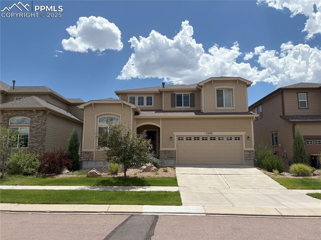 Caption: View of front of property featuring stone siding, driveway, and an attached garage