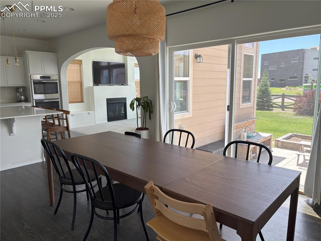 Image 10 of 35: Dining area with dark wood finished floors, a glass covered fireplace, and 