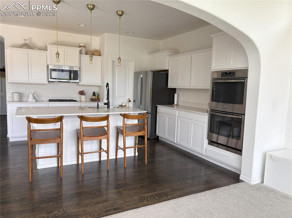Image 14 of 35: Kitchen featuring stainless steel appliances, arched walkways, light counte