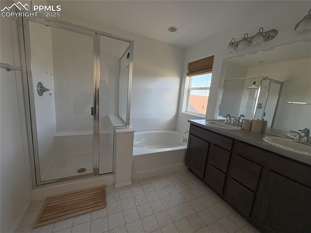 Image 21 of 35: Primary bathroom featuring a shower stall, double vanity, and tub