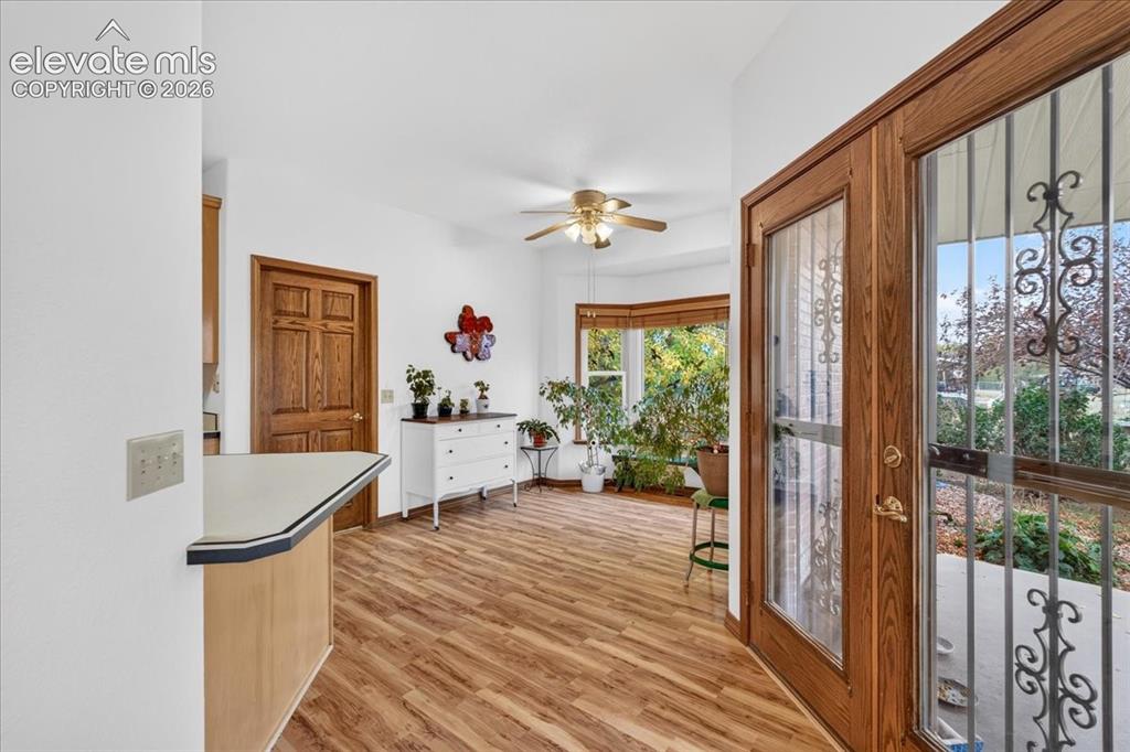 Image 10 of 44: Wood-finish flooring, bay window, ceiling fan, and wooden entry door with d