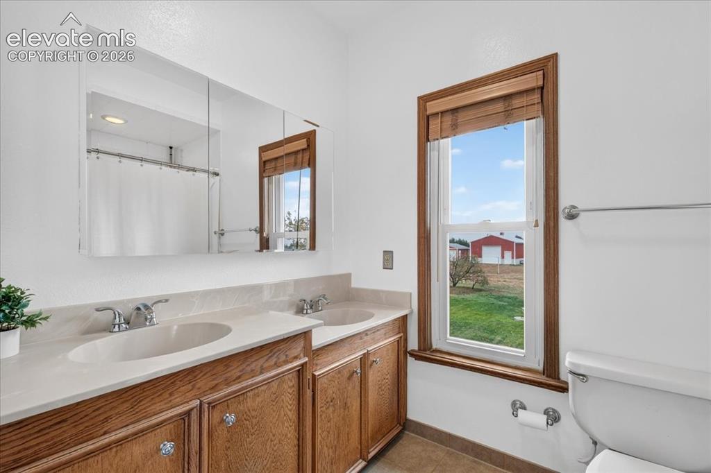 Image 18 of 44: Double vanity with wood-finish cabinetry, solid-surface countertop, dual in