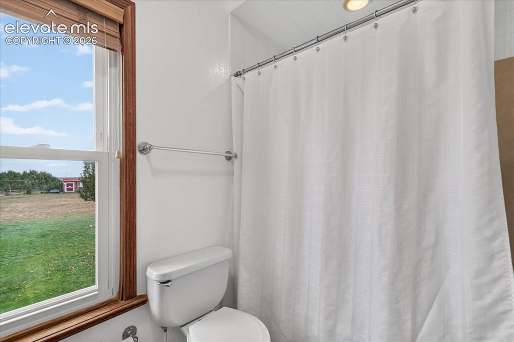 Image 19 of 44: Full bathroom featuring a window with wood trim, white toilet, and chrome h