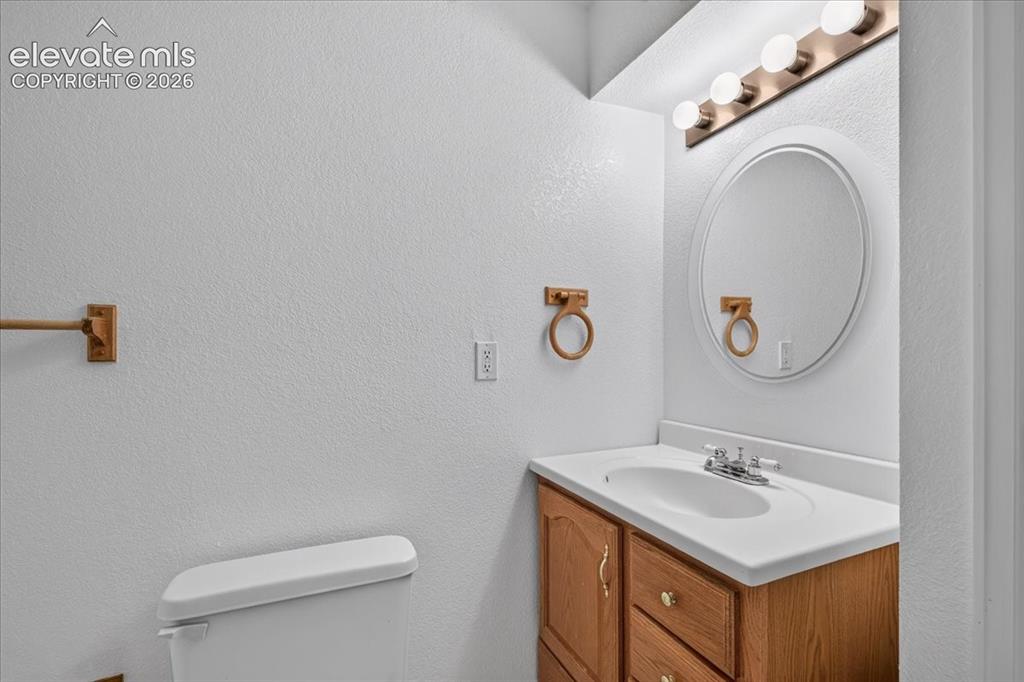 Image 29 of 44: Vanity featuring a light wood cabinet, integrated molded sink, circular mir
