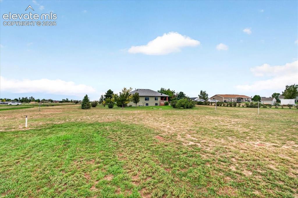 Image 33 of 44: Expansive lot featuring open grounds, mature trees, and a detached residenc