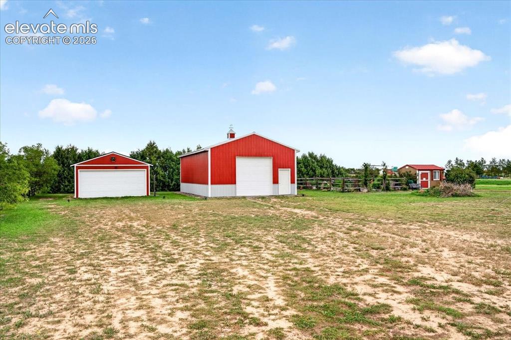 Image 34 of 44: Expansive grounds featuring two detached metal-sided garages and a smaller 