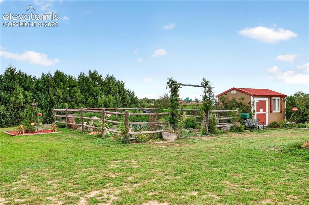 Image 35 of 44: Expansive backyard featuring a rustic rail fence, a dedicated gardening are