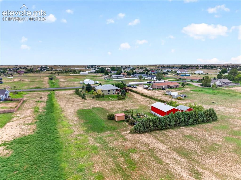 Image 36 of 44: Expansive acreage featuring a red metal-sided outbuilding, mature evergreen