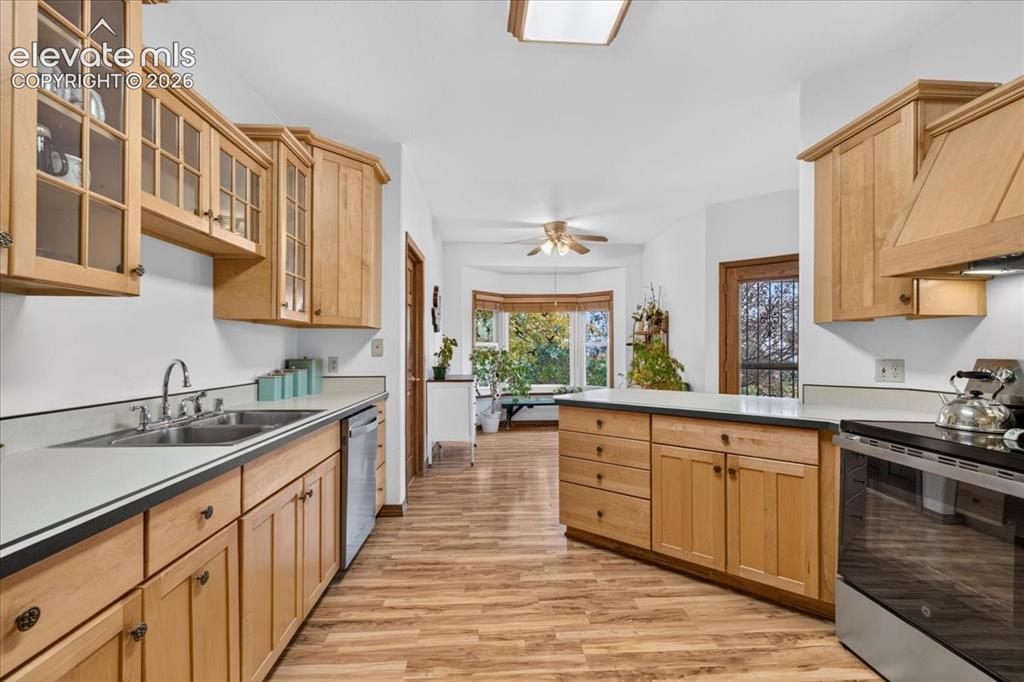 Image 6 of 44: Kitchen featuring natural wood cabinetry, solid surface countertops, wood-f