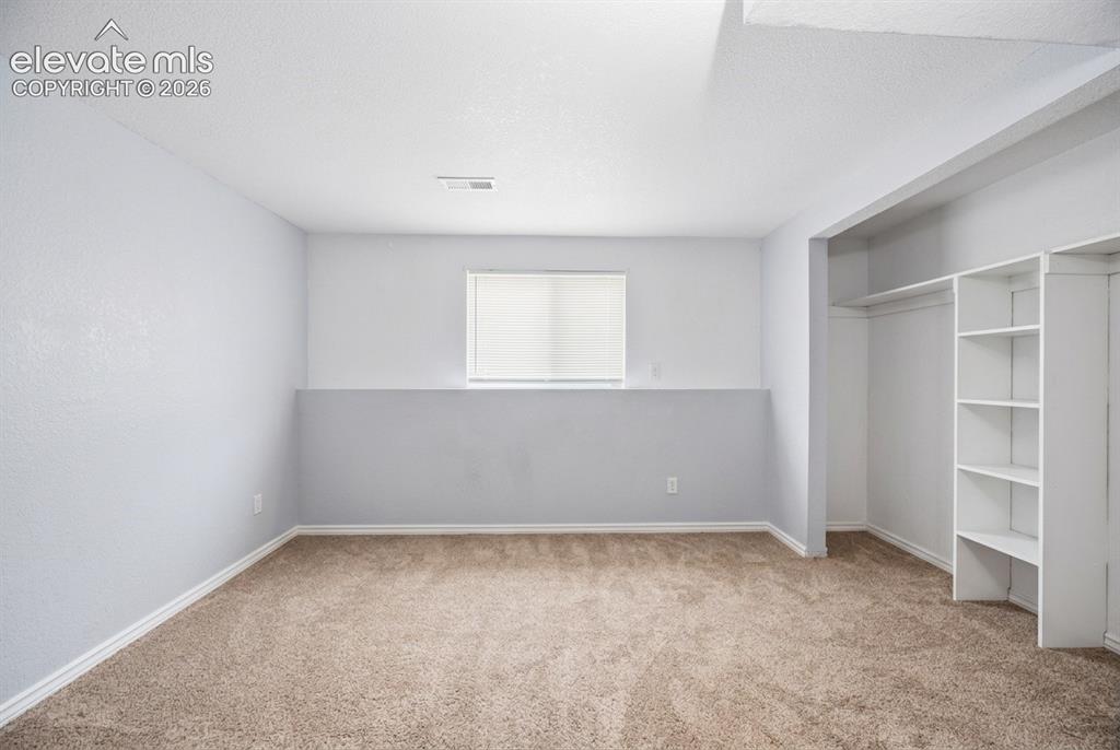 Image 14 of 20: Recessed window with privacy blind, carpeted flooring, and built-in shelvin