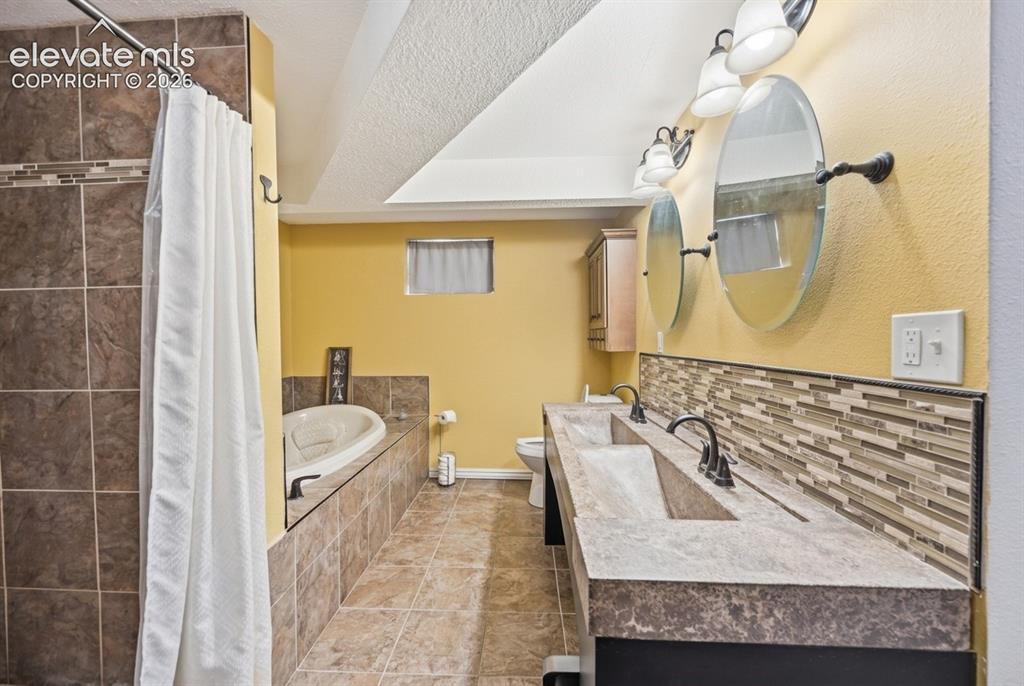 Image 16 of 20: Dual vanity with integrated sinks, mosaic tile backsplash, jetted soaking t