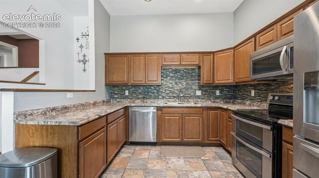 Image 4 of 20: Kitchen featuring abundant wood cabinetry, stainless steel appliances, a mo