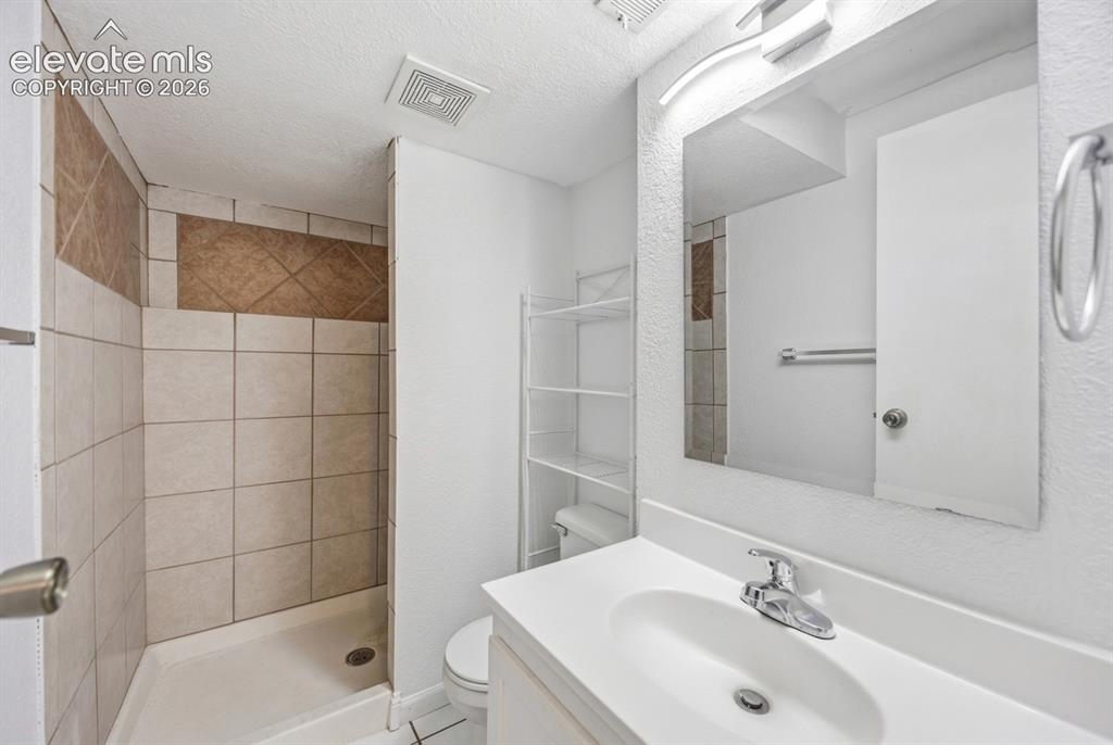 Image 8 of 20: Shower with tile surround and accent band, single vanity with integrated si
