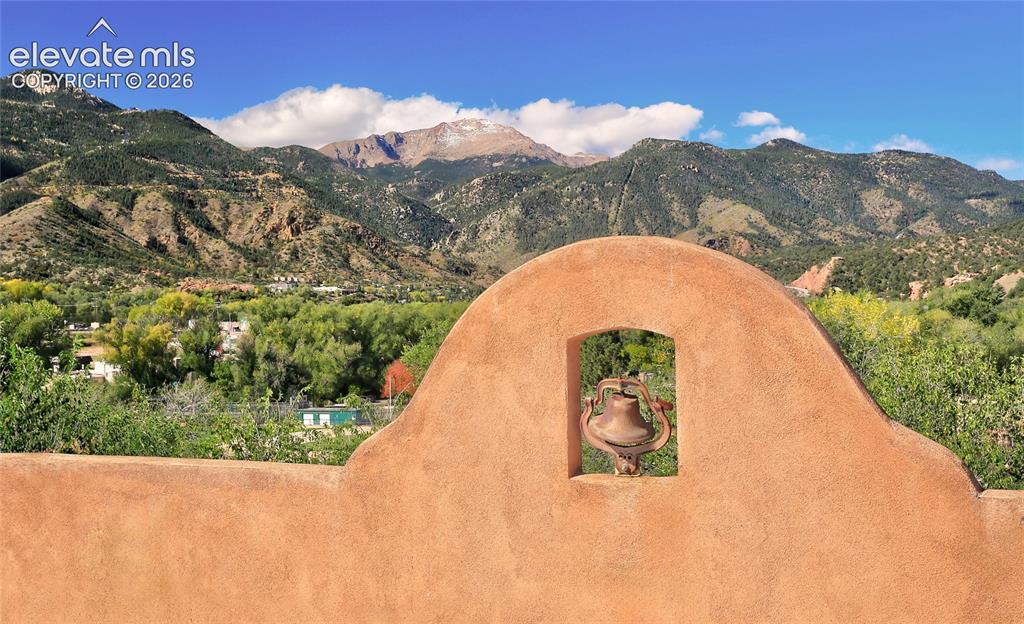 Caption: Stucco parapet wall with integrated bell niche and mountainous landscape backdrop